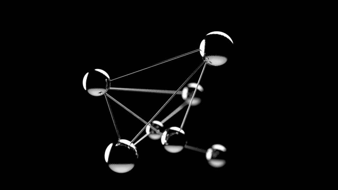 A 3D rendering of six shiny metallic spheres connected by thin rods, forming a geometric structure against a black background.