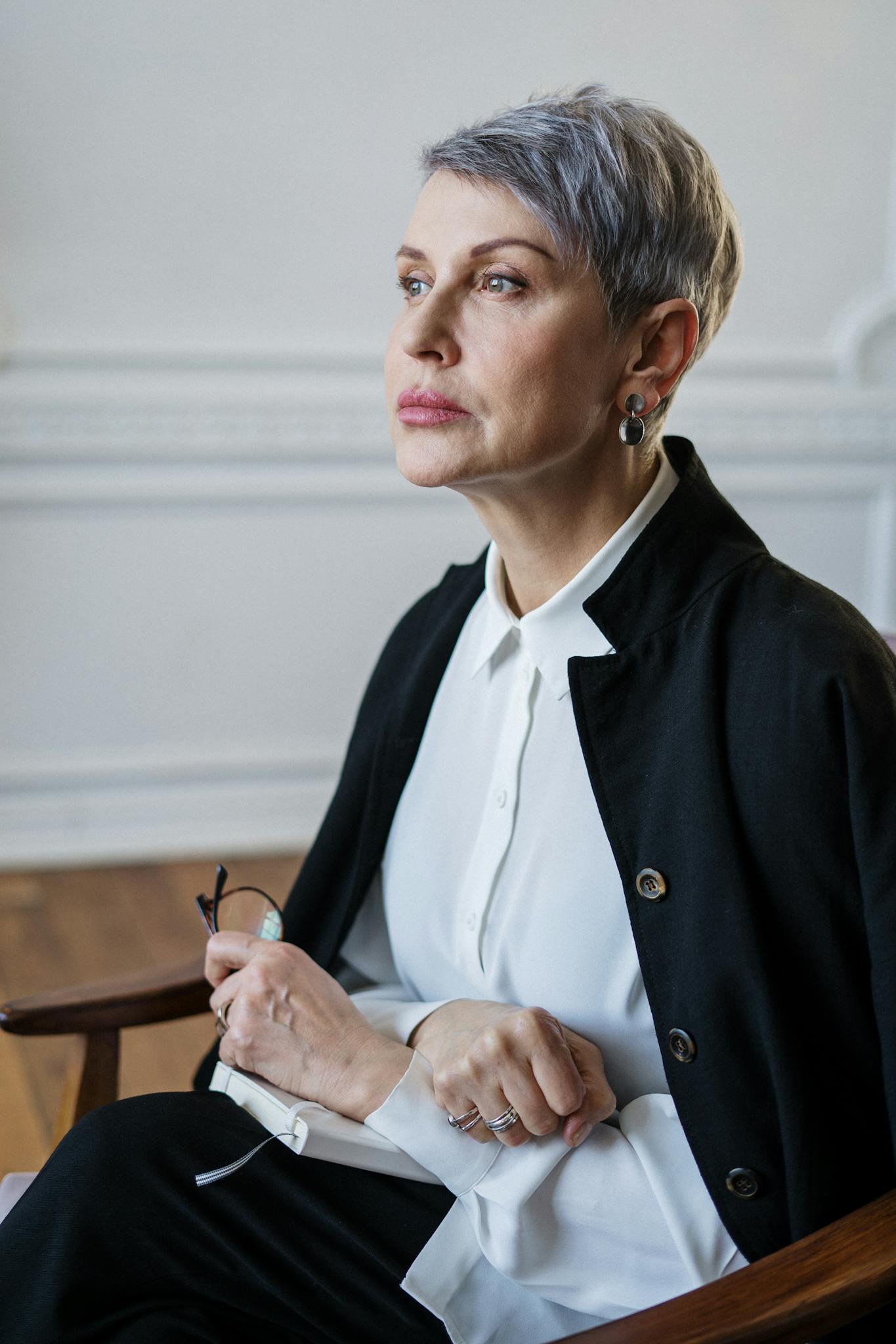 A mature woman seated thoughtfully in a professional office setting.